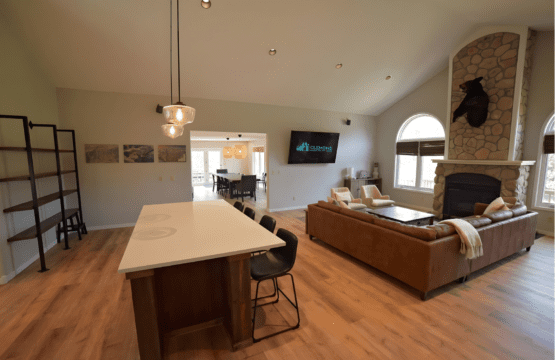 Contemporary kitchen island and cozy living area with fireplace and large windows in an open-concept vacation rental.
