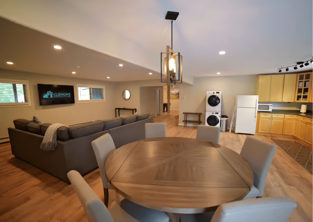 Round dining table beside comfortable living room seating in a bright open-plan vacation rental interior.