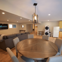 Round dining table beside comfortable living room seating in a bright open-plan vacation rental interior.
