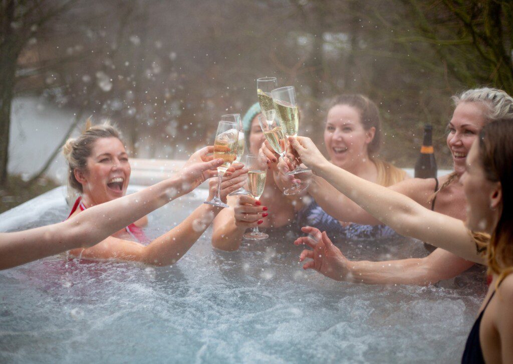 Friends celebrating in a hot tub at a Silverthorne cabin with hot tub, toasting with champagne in winter.