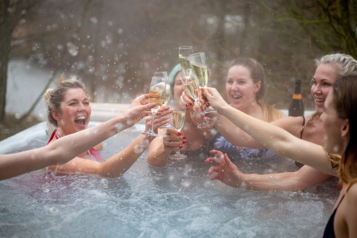 Friends celebrating in a hot tub at a Silverthorne cabin with hot tub, toasting with champagne in winter.