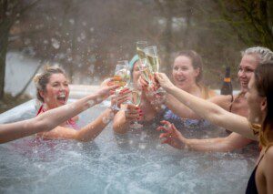Friends celebrating in a hot tub at a Silverthorne cabin with hot tub, toasting with champagne in winter.