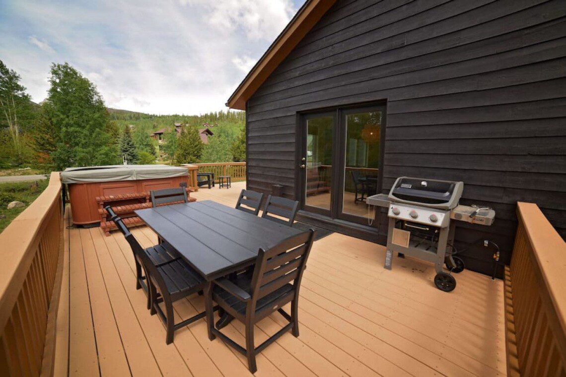 Mountain cabin deck with outdoor dining table, grill, and hot tub near Dillon Marina boat rental in Colorado.
