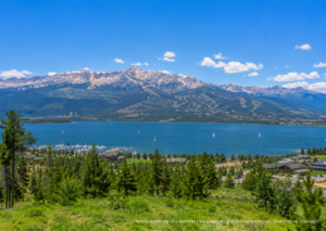 Lake Dillon boat rental on a sunny summer day with a pontoon boat cruising across the lake surrounded by Colorado mountains